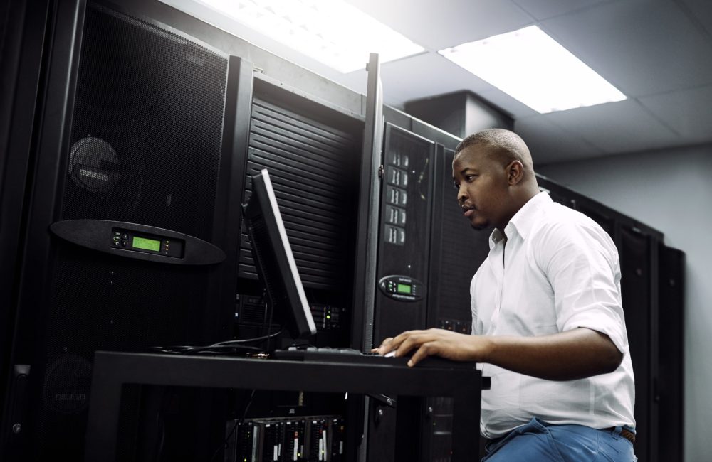 IT support, black man or coding on laptop in server room for big data, network glitch or digital website. Code, fixing or technician typing on computer testing UX, programming or software development.